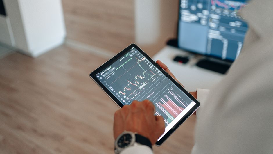 Ruke koje koriste tablet za online trgovanje i analizu tržišta